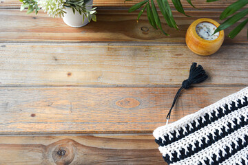 crocheted toiletry bag on wooden background with plants and candle