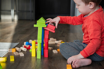 Child, little boy, toddler playing with eco-friendly wooden bricks or blocks. Children’s game...