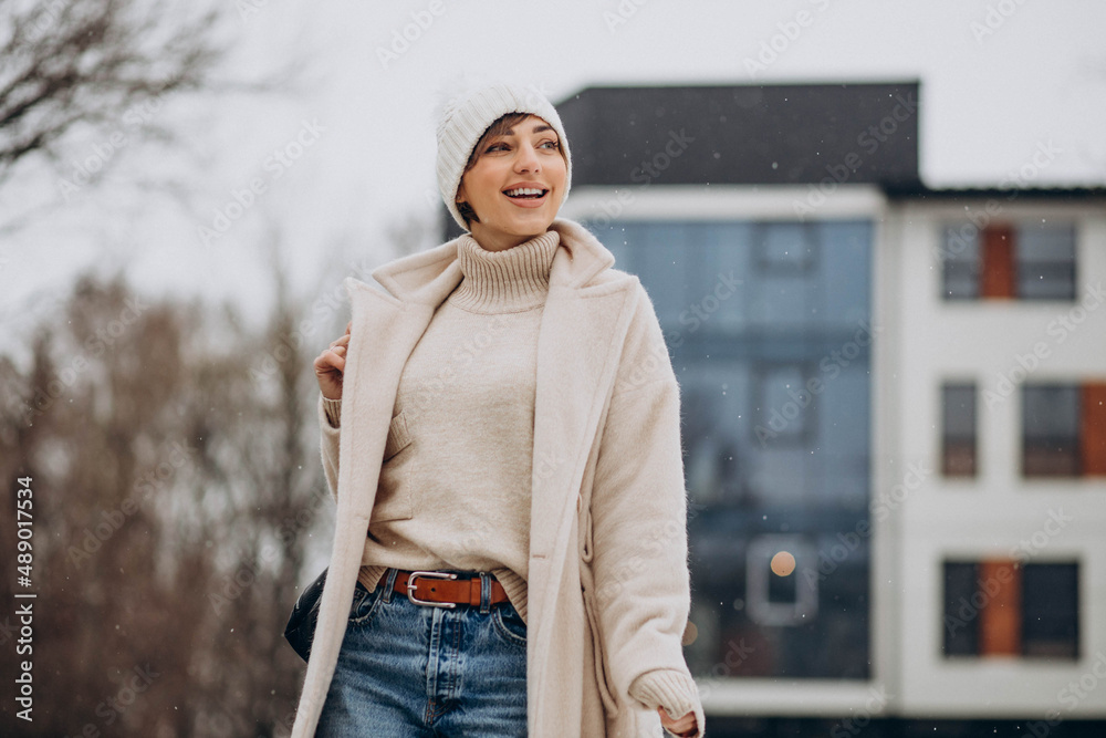 Wall mural woman with bag wearing winter coat walking in the street