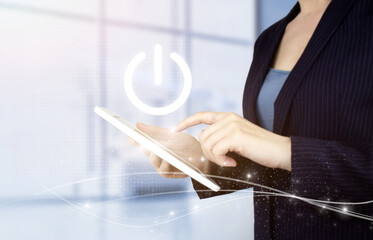 Start or shut down concept. Hand touch white tablet with digital hologram pressing button on virtual screen sign on light blurred background.