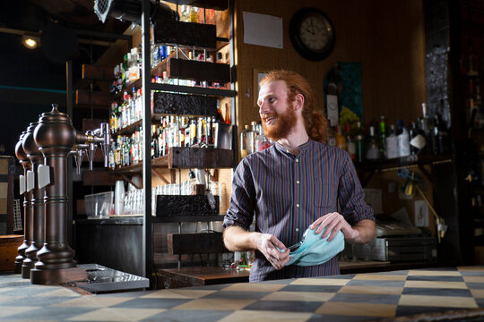 Positive barman wiping wineglass in bar