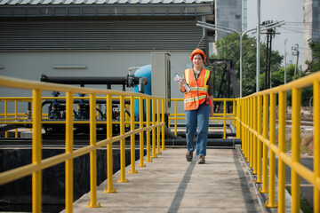 Obraz premium Engineer woman onsite check waste water treatment plant. Young woman service engineer on waste water treatment plant.