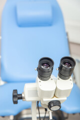 Colposcope closeup on the background of gynecological chair.