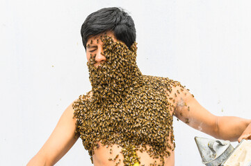 Beekeeper covered by bees, he has the queen bee on his neck so all the bees stick to his body....