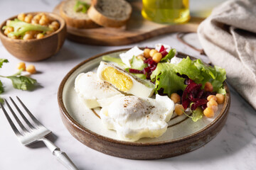Easter breakfast or brunch. Poached egg and beet salad with spinach, cheese feta, chickpeas on a marble tabletop.