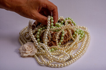 hand holding multiple pearl necklaces