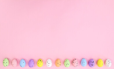 Pastel Easter eggs on bright pink background neatly ordered on the bottom. Spring holidays copy...