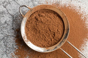 Cacao en polvo dentro de un tamiz sobre un fondo de mármol gris. Vista superior y de cerca. Primer plano