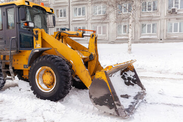 Big orange tractor cleans up snow from the road and loads it into the truck. Cleaning and cleaning...