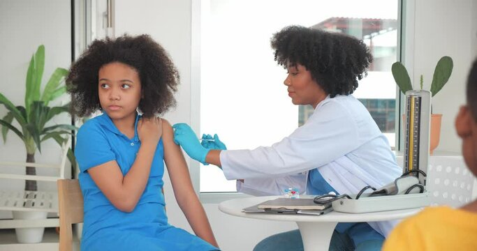 African-American kids getting vaccine in clinic or hospital, with hand nurse injecting vaccine to get immunity for protection. vaccine for kids concept.