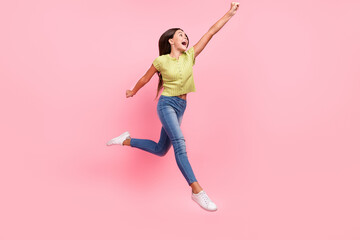 Fototapeta na wymiar Profile photo of sportive energetic lady jump raise fist wear green top jeans footwear isolated pink color background