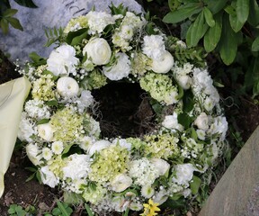 Weiße Blumen im Trauerkranz nach Beerdigung auf dem Friedhof