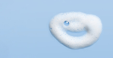 Soap cleanser foam texture. Children shampoo bubbles funny face on blue background. Cosmetic foamy...