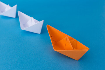 Business Leadership Concept - Orange Color Paper boat Origami leading the rest of the white paper...