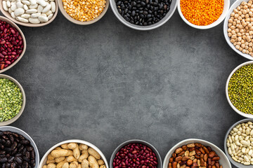Frame of various types of legumes in bowls, green and yellow peas, chickpeas and peanuts, colored beans and lentils, mung beans and beans, top view, copy space