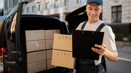 A male driver in uniform in courier delivery, carries groceries in a box.