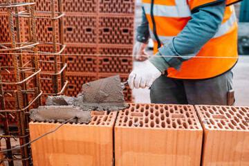 Close up of industrial bricklayer installing bricks on construction site