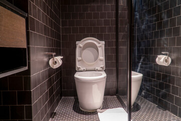 Black bathroom have white toilet and white towel