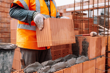 Portrait of Construction worker bricklayer using bricks and mortar for building walls. industry details and construction equipment - obrazy, fototapety, plakaty
