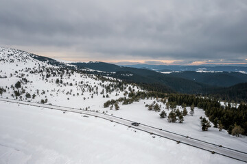 Fototapeta na wymiar Aerial drone photography of a snowy mountain with a car on the road. Winter landscape countryside.