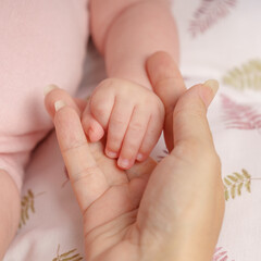 Petite main de bébé nouveau né dans la main de sa maman. Amour, tendresse, naissance.