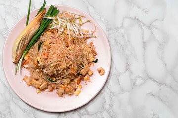 Fried rice noodle Pad thai has egg vegetable on white table.