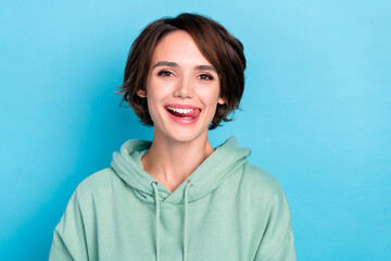 Photo of pretty shiny woman wear green sweatshirt showing tongue smiling isolated blue color background