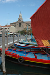 Fototapeta na wymiar Chioggia , Venezia. Barca con vela da regata sul fronte della Cattedrale di Santa Maria Assunta 