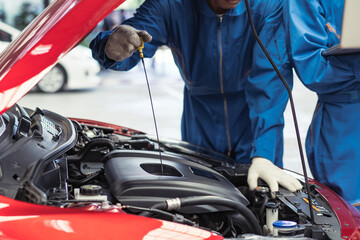 automobile mechanic checking oil level in the car engine at auto garage shop. after repair service concept