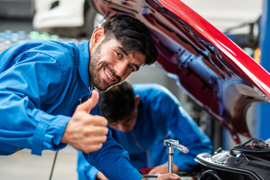Happy smile Caucasian male mechanic showing thumbs up while checking car damage, diagnostic and repairing vehicle at garage automotive, motor technician maintenance after service concept