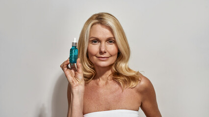 Mature woman holding bottle with cosmetic oil