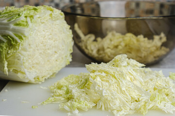 Cut bulb of Chinese cabbage on a cutting board. Low-calorie food, cooking a dietary meal. Selective focus, blurred background.