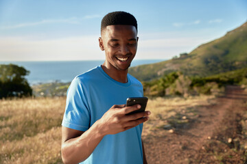 Black young Adult male athlete about to start his trail run. Setting timer on his smartphone