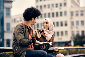 Happy Middle Eastern woman and her college friend talk at campus.