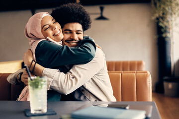 Young happy Muslim couple in love embraces in a cafe.