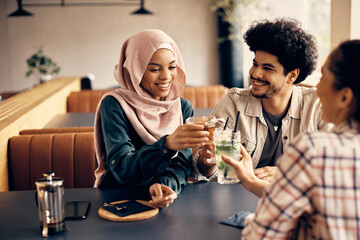 Happy multiracial group of friends toast while celebrating their friendship in cafe.