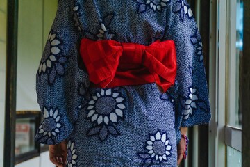 Woman wearing a blue yukata tied with a red bow in a traditional Japanese house