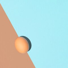 Easter minimal flat lay idea with an egg on pastel blue and brown background. Creative spring celebration concept, minimal overhead arrangement. Optimistic mood.