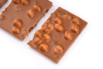 Macro photo of Chocolate bar. Broken pieces over white background. Pieces of milk chocolate with nuts isolated on white background