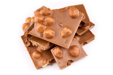 Macro photo of Chocolate bar. Broken pieces over white background. Pieces of milk chocolate with nuts isolated on white background