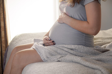 Healthy pregnant woman holding her belly in a cozy home environment