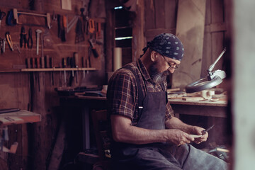 Fototapeta na wymiar Spoon master in his workshop with wooden products and tools