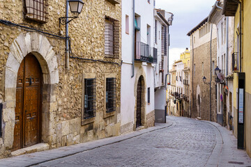 Narrow cobblestone floor street and medieval doors in the city of Cuenca, Spain.