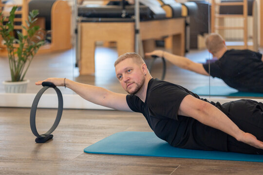 Male fitness Pilates trainer shows exercises on special simulators. Rubber rings for stretching. High quality photo