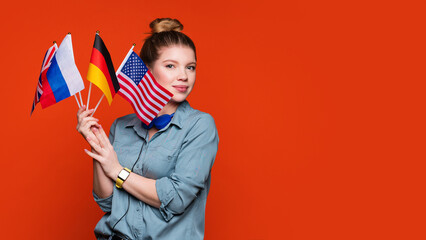 Caucasian student girl holds set small flags. Study abroad concept. International student exchange program. Female student recommending foreign language studying school. Copy Space