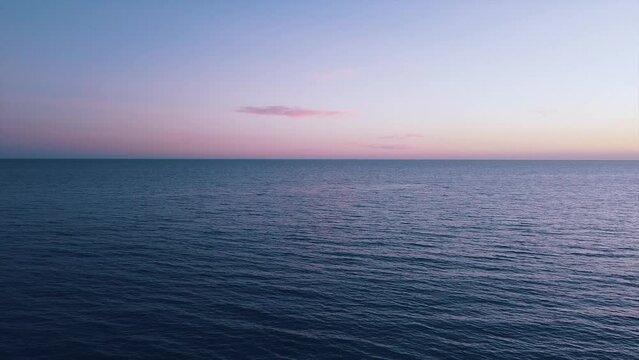 Vista del horizonte al paso sobre el mar mediterr&aacute;neo con cielo de atardecer y nubes peque&ntilde;as de color rosado anaranjado