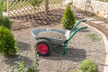 Two-wheeled wheelbarrow loaded with river pebbles on the recreation area under construction in the...