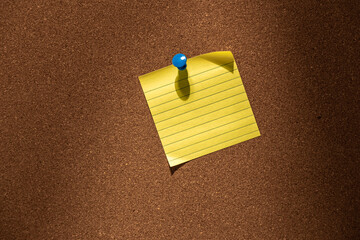 yellow sticky note with guideline pinned to a cork board with a pin