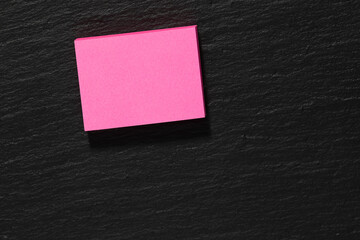 pink sticky note block on a slate background