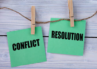 CONFLICT and RESOLUTION - words on green pieces of paper with clothespins on a light wooden...